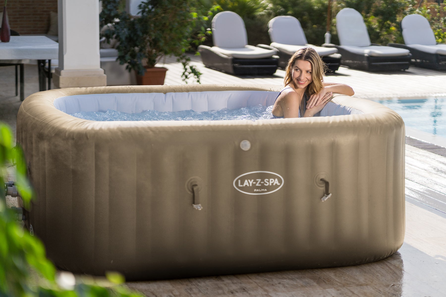 A woman unwinds in an inflatable Palma Hydrojet Pro hot tub, enjoying a soothing and relaxing experience near the pool