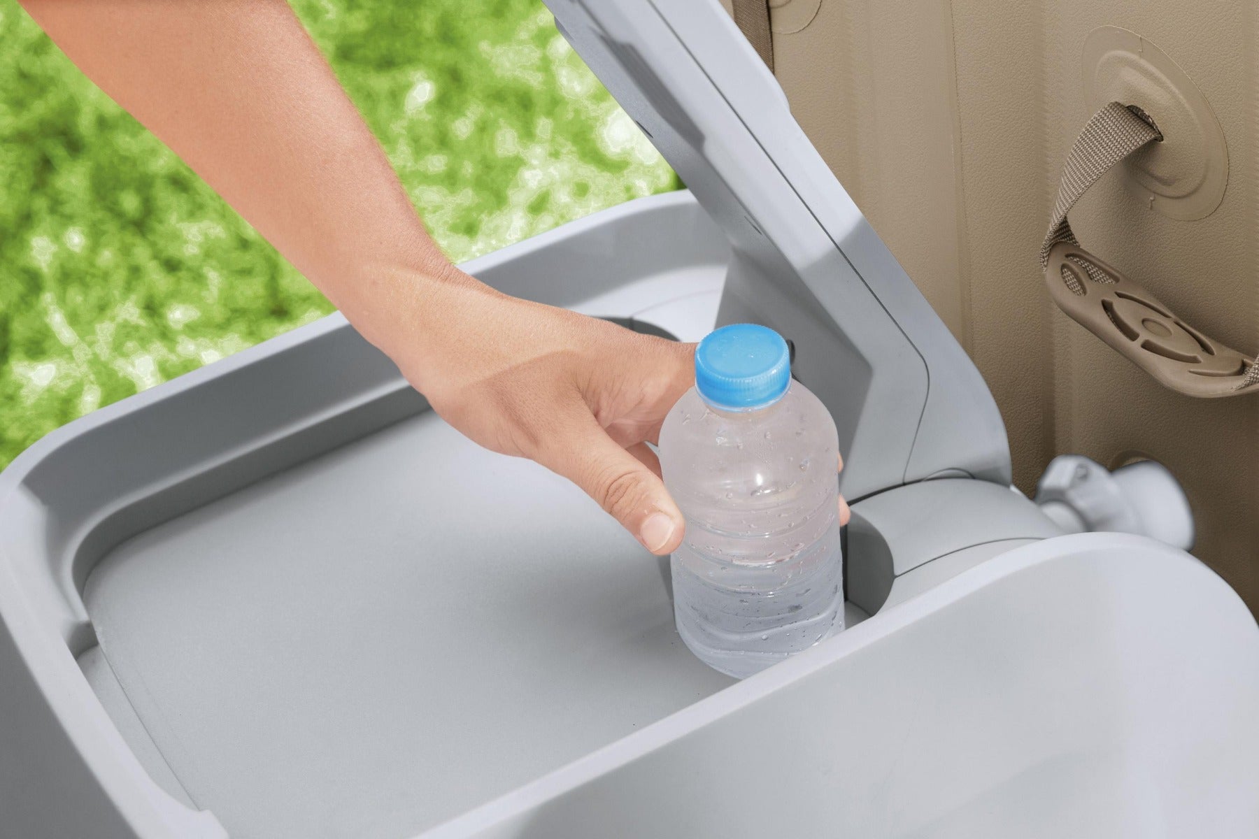 A person places their water bottle into a integrated drinks holder in Lay-Z-Spa Hydrojet pro pump next to an inflatable Palma Hot Tub