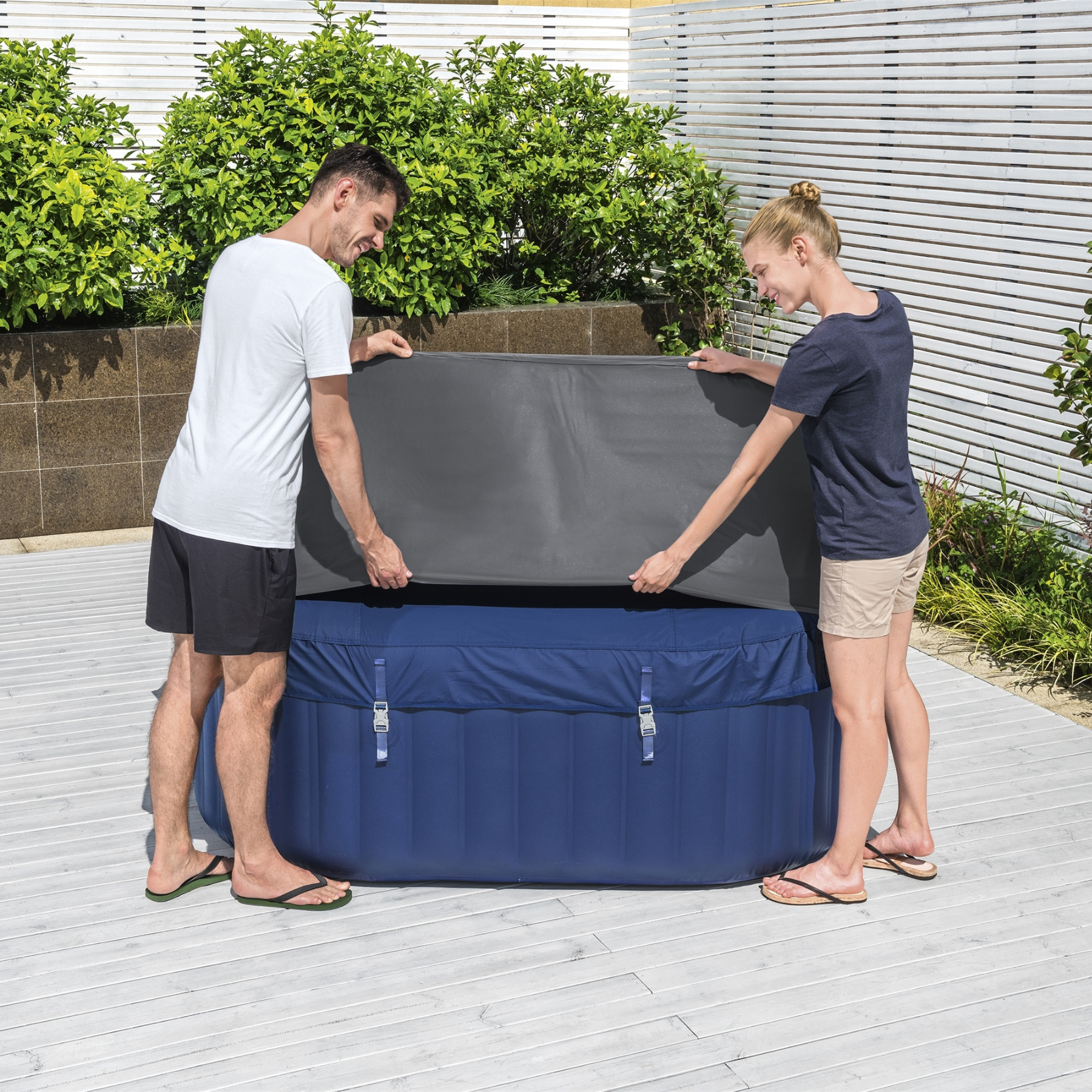 two people fitting a square thermal cover over a hot tub